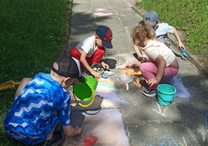 Dzieci rysują kredą na chodniku